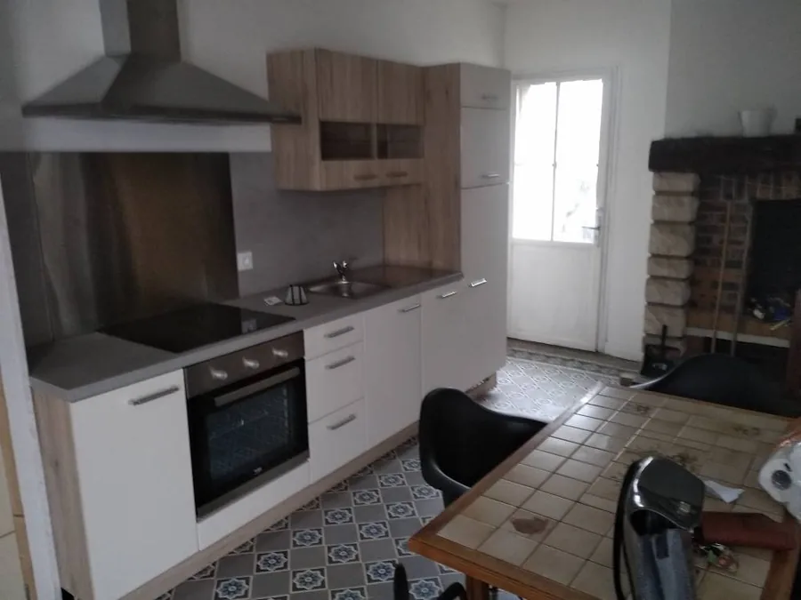Cuisine équipée sur carreaux anciens — Meubles bois et blanc, hotte inox, le carrelage d'époque conservé et nettoyé.