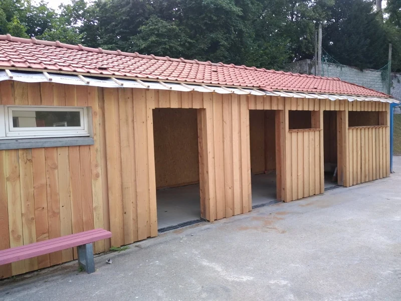 La même extension, façade jardin — Le bardage vertical file d'un bout à l'autre, l'œil-de-bœuf marque l'entrée de la pièce.