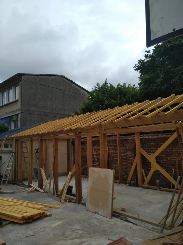 Extension en cours · ossature et brique — La structure montée sur la dalle, la brique de la maison reprise pour le raccord, la bétonnière encore sur place.