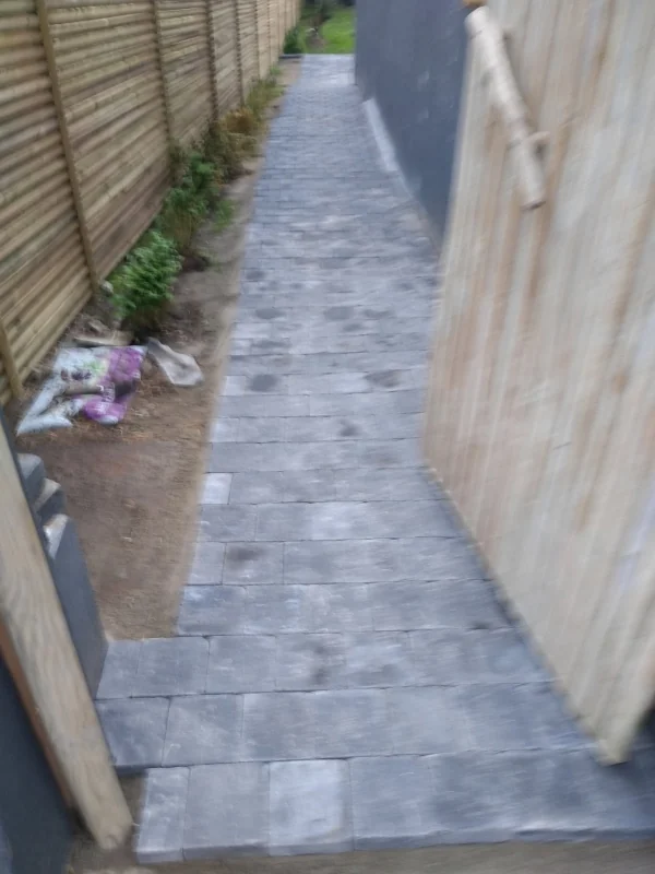 Allée pavée — Pavés posés en arc devant une maison de brique, bordures alignées.